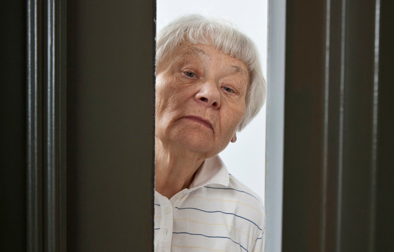 A woman peering around a door looking worried